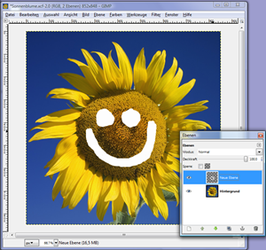 GIMP, Hauptfenster mit Sonnenblumen-Foto im Hintergrund und einem Smiley als zweite Ebene darübergelegt