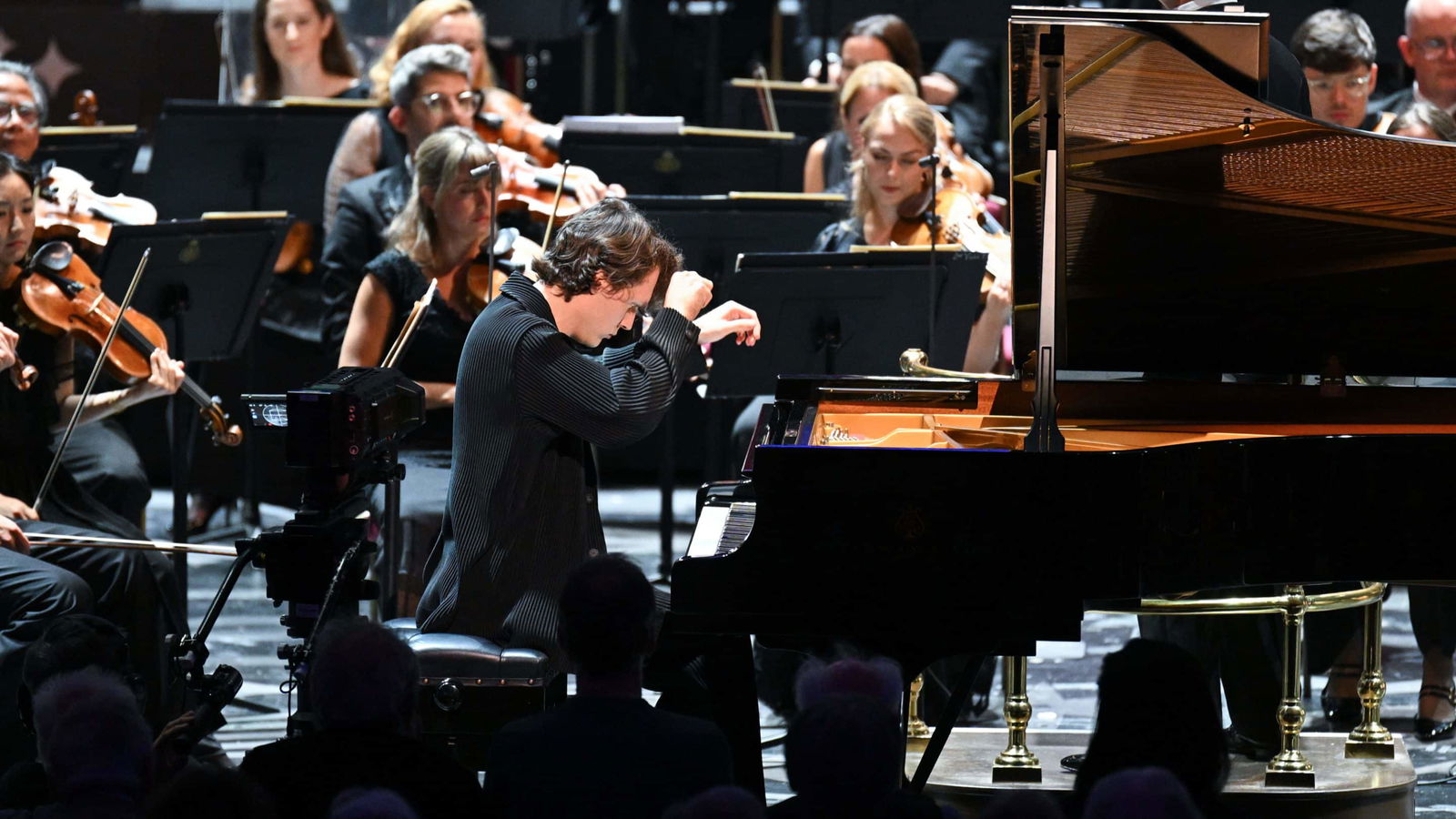 Pianist spielt vor einem Orchester bei Konzert.