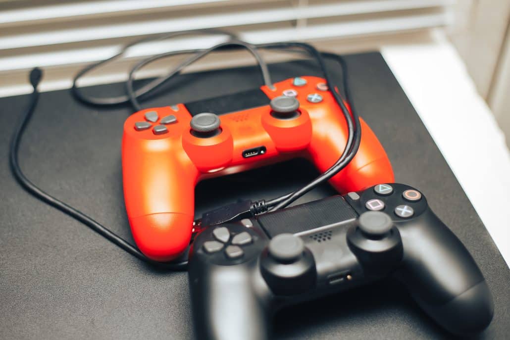 Zwei Spielcontroller, rot und schwarz, auf einem Tisch.